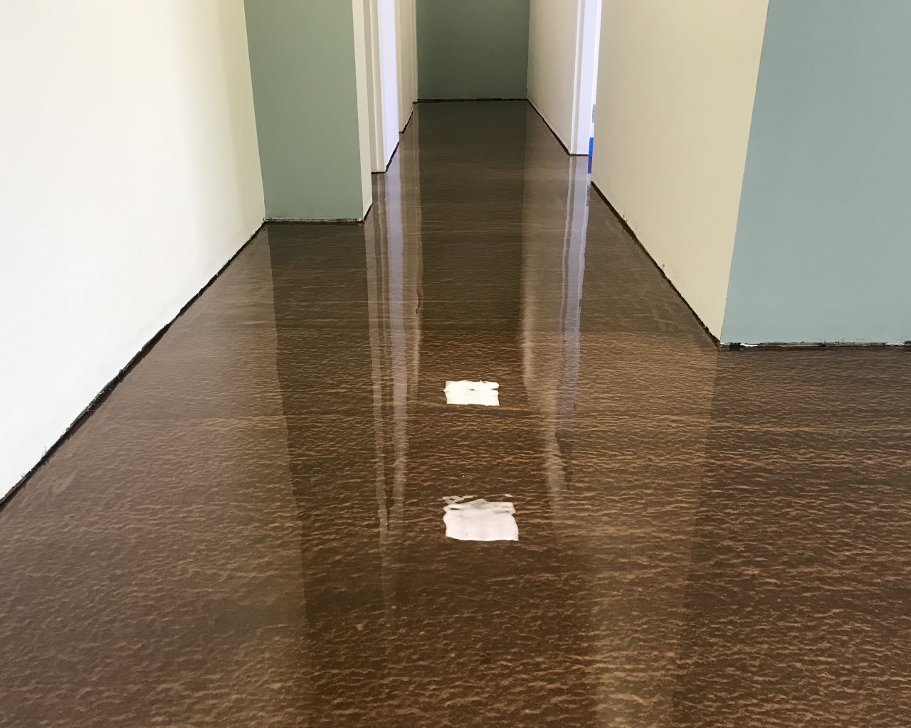 Metallic epoxy floor with a custom yellow sunburst logo in a retail shop